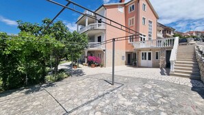 A two-story building with a balcony, stone-paved courtyard, and a staircase leading to the upper floor. - Wohnung mit Terrasse und Meerblick by Interhome (Crikvenica)