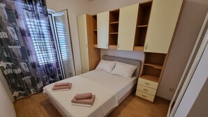 A bedroom with a bed, two bedside tables, a wardrobe, and a window with curtains. - Wohnung mit Terrasse und Meerblick by Interhome (Crikvenica)