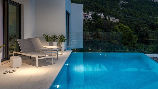 Ein moderner Poolbereich im Freien mit freiem Blick auf eine gebirgige Landschaft.