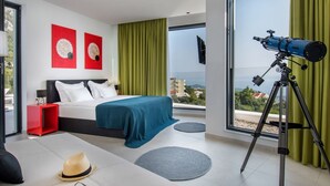 Ein modernes Schlafzimmer mit einem großen Bett, einem Teleskop und Blick auf die Stadt.