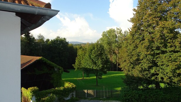 A view from a balcony overlooking a green lawn, trees, and a distant mountain range. - Haus Victoria by Interhome (Schöllnach)