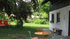 A patio with a table and chairs, a wooden bench, and a building with windows and a door. - Haus Victoria by Interhome (Schöllnach)