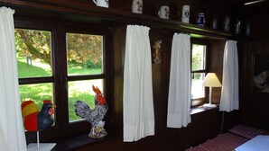 A room with a bed, a window with curtains, a lamp, and a rooster decoration. - Haus Victoria by Interhome (Schöllnach)
