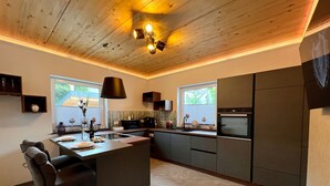 A modern kitchen with a central island, dark cabinetry, and a built-in oven. - Elegante Ferienwohnung in Hollnich mit Garten by Interhome (Auw)