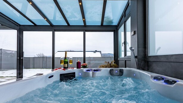 A hot tub with a glass ceiling, a bottle of champagne, and two glasses on the edge. - Elegante Ferienwohnung in Hollnich mit Garten by Interhome (Auw)