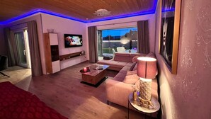 A modern living room with a wooden ceiling, a flat-screen TV, a sofa, a coffee table, and a lamp. - Elegante Ferienwohnung in Hollnich mit Garten by Interhome (Auw)