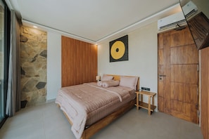 Quarto com parede de pedra, painel de madeira, cama com roupa de cama rosa, mesa de cabeceira e guarda-roupa de madeira.