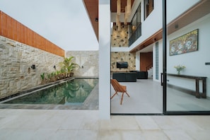 Um interior moderno com parede de pedra, piscina e área de estar.