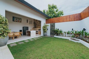 Uma casa moderna com cozinha, sala de jantar e um pequeno quintal com gramado e plantas em vasos.