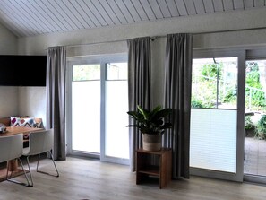 A modern living room with a dining area, large sliding glass doors, and a potted plant. - Apartment Reitz by Interhome (Fritzlar)