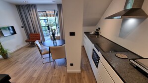 A modern kitchen with a built-in oven, a dining area with a round table and chairs, and a large window with curtains. - VIL Studio-Wohnung in Crikvenica, Kvarner Bucht by Interhome (Crikvenica)