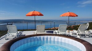 En pool på taket med två orangea parasoller och solstolar, med utsikt över ett vackert landskap.