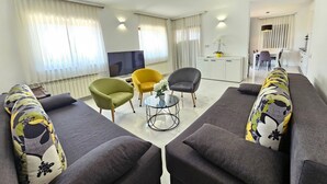 Uma sala de estar moderna com um conjunto de sofás, uma televisão e um espaço para refeições.