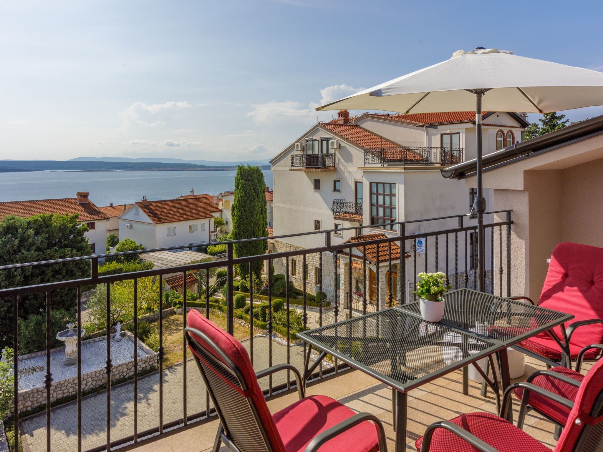 Ein Balkon mit Tisch und Stühlen mit Blick auf einen See und Gebäude.