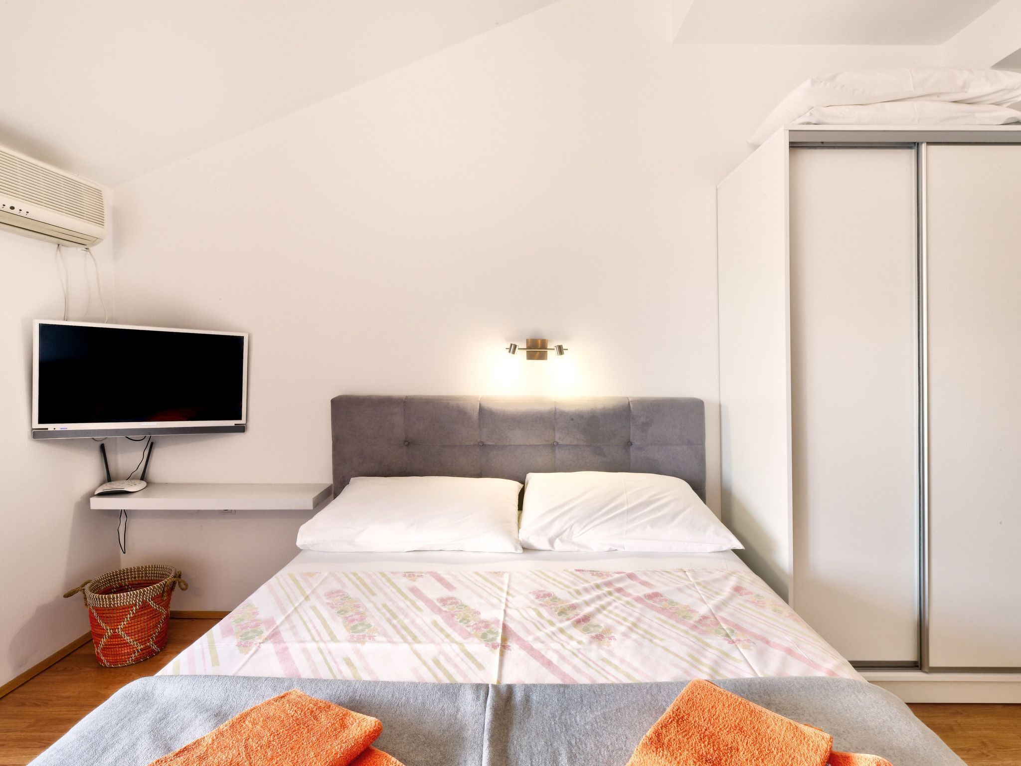 A bedroom with a bed, a television, a wall-mounted heater, and a wardrobe.