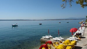 Ein Strand mit klarem Wasser, Liegestühlen und Sonnenschirmen.