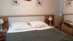Habitació d'hotel amb un llit, dues taules de nit i tres quadres penjats a la paret.