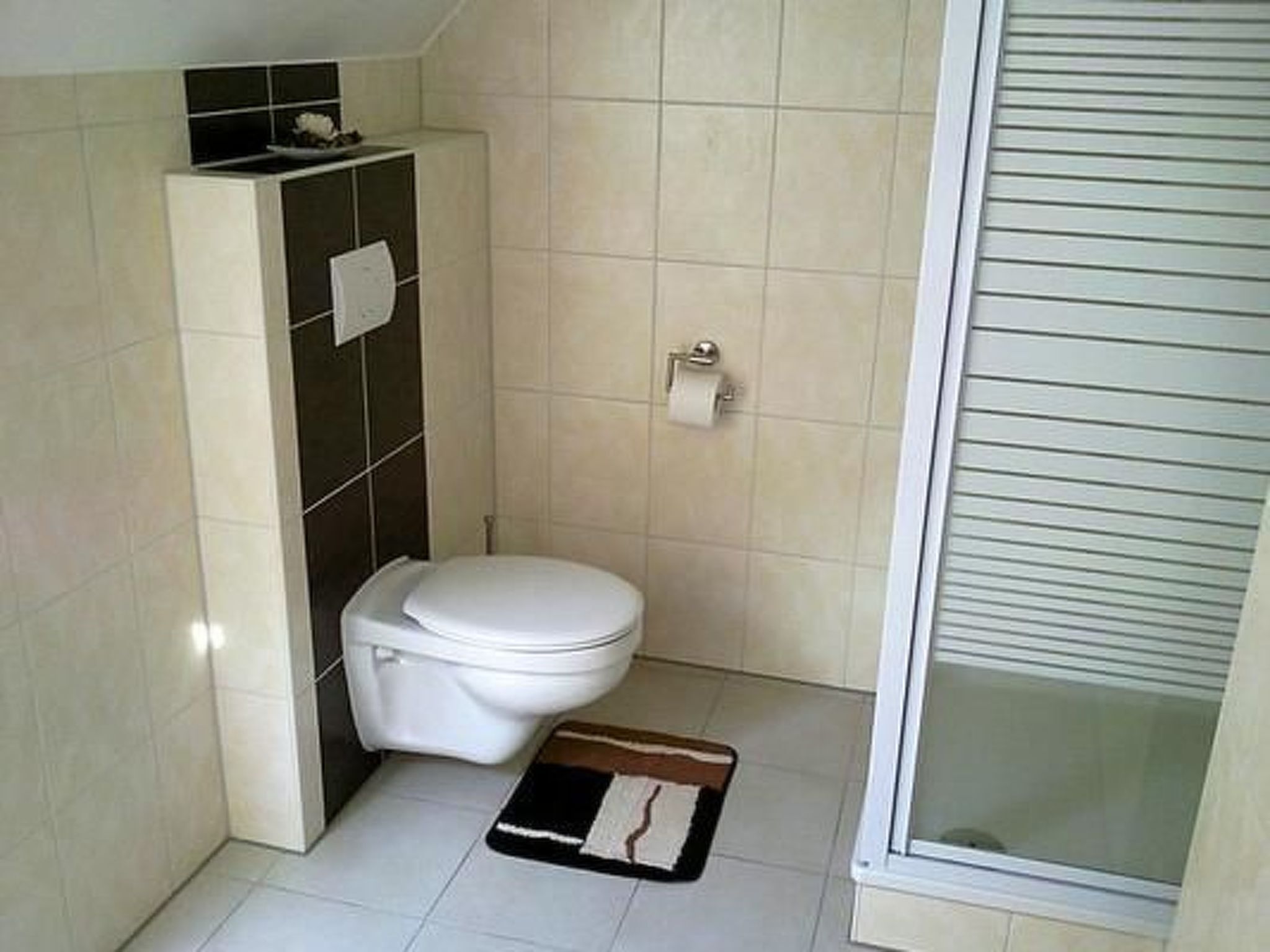 Une petite salle de bain comprenant des toilettes, un porte-serviettes et une porte de douche.