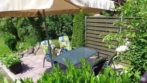 An outdoor patio with a table and two chairs, surrounded by greenery and a wooden fence. - Domizil für zwei by Interhome (Binz)