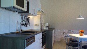 A modern kitchen with a built-in oven, microwave, and sink. There is a dining area with a table and chairs. - Domizil für zwei by Interhome (Binz)