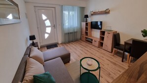Una sala de estar moderna con un sofá, una mesa de centro, un televisor y un pequeño comedor.