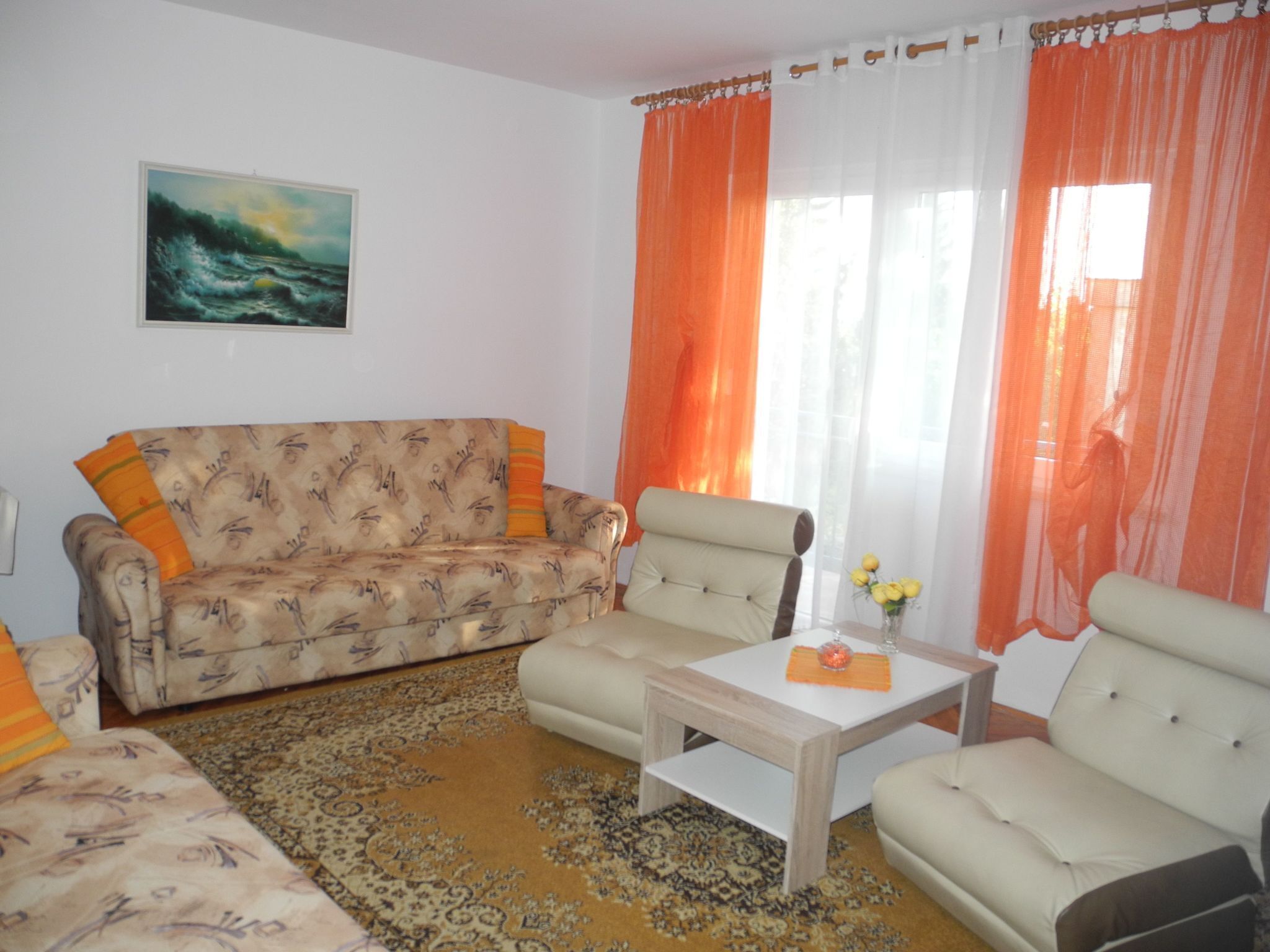A living room with a patterned sofa, a coffee table, and a painting on the wall.