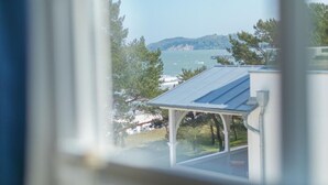 Vista desde una ventana sobre un cuerpo de agua, un muelle y una cadena montañosa distante.