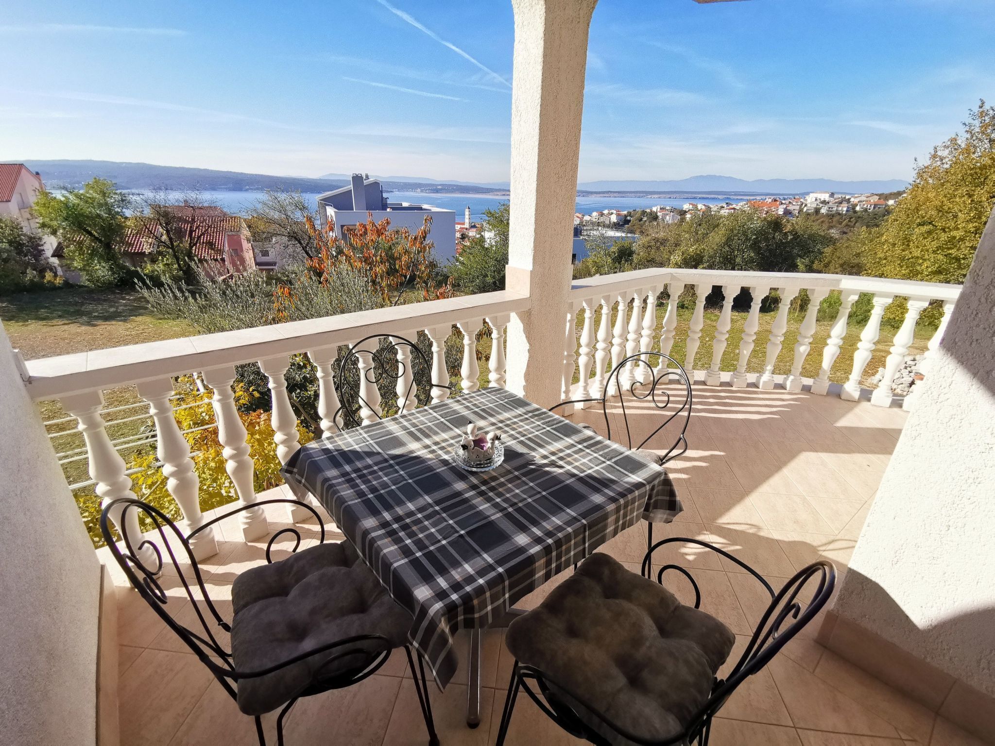 Ein Balkon mit Tisch und Stühlen, der einen schönen Blick auf eine Küstenstadt und das Meer bietet.