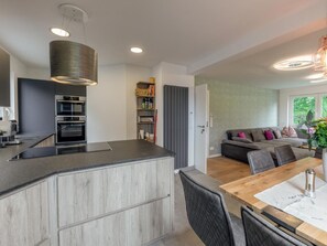 A modern kitchen with built-in appliances, a dining area with a wooden table and chairs, and a living room with a sofa and cushions. - Traum Wohnung direkt am Bodensee mit Seesicht by Interhome (Friedrichshafen)