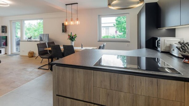 Una cocina moderna con una isla central, iluminación colgante y vistas al exterior.