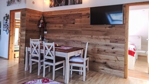 A dining area with a wooden wall, a TV mounted above the wall, and a rustic decor including a scarecrow. - Haus Maria Hochschwarzwald, Garten umzäunt, Wald by Interhome (Menzenschwand)