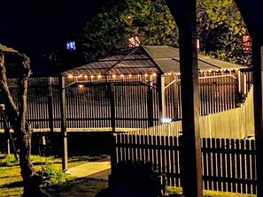 A gazebo with a metal roof and string lights, surrounded by a wooden fence. - Haus Maria Hochschwarzwald, Garten umzäunt, Wald by Interhome (Menzenschwand)