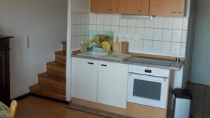 Une cuisine compacte avec des meubles en bois, un four encastré et un pare-feu en carreaux.