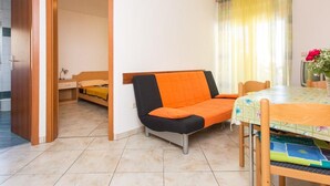 En kompakt opholdsstue med sofa, lille bord og spiseplads.