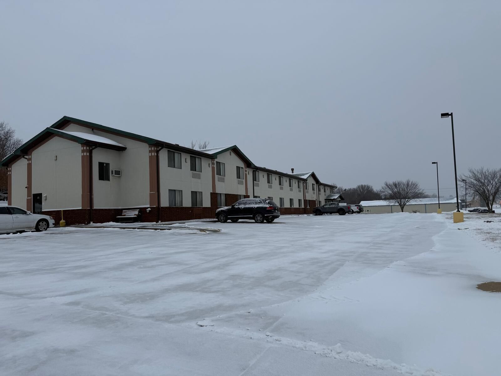 A row of motel buildings with a parking lot in front.