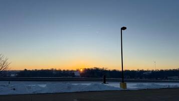 A parking lot with snowbanks and a street lamp.