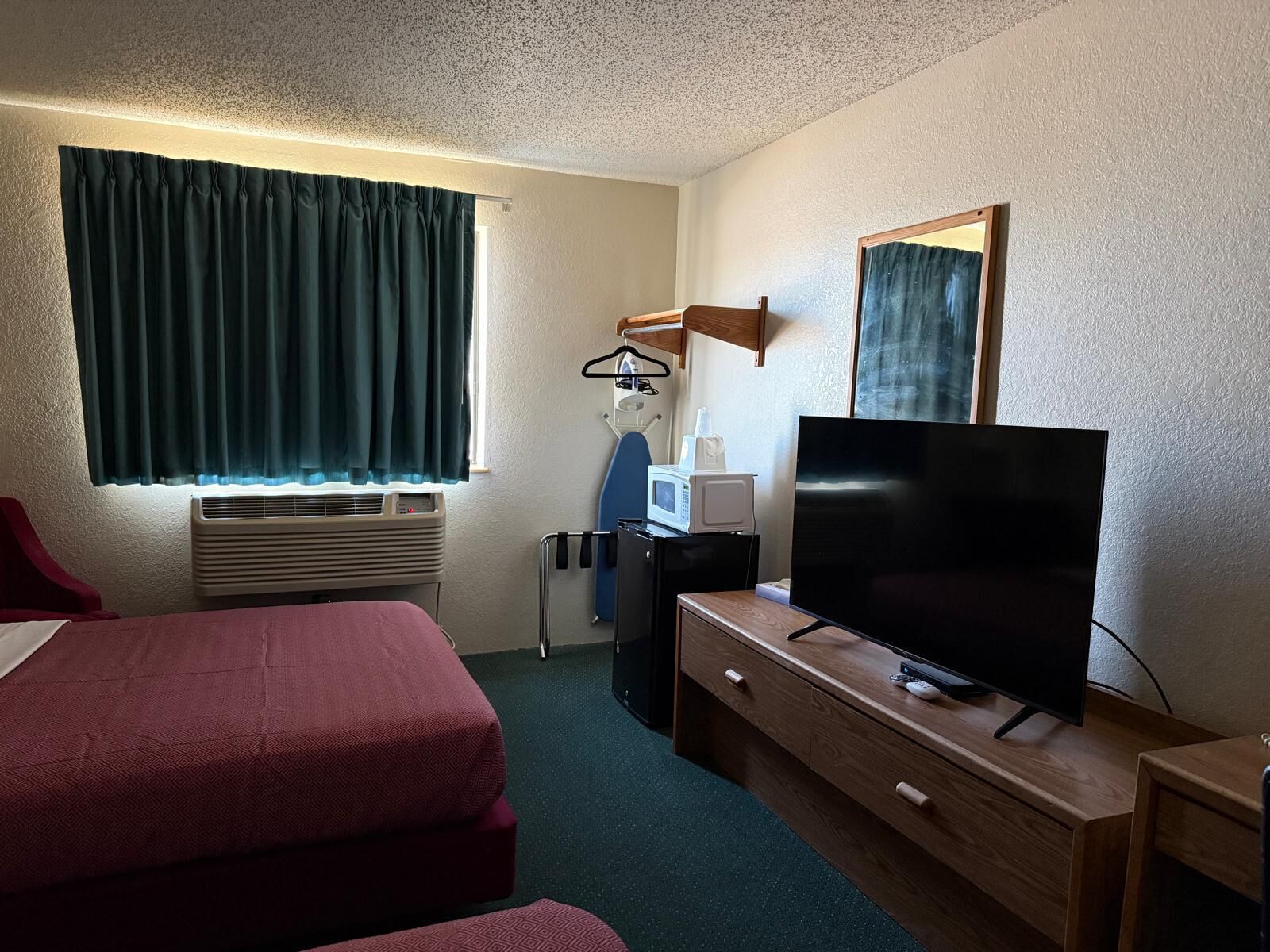 A hotel room with a bed, a TV, a microwave, and a small desk.