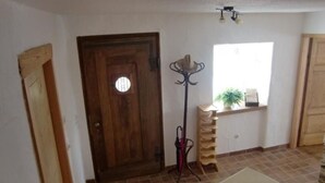 A room with a wooden door, a tall floor lamp, a window with a plant, and a tiled floor. - Little Stonehouse by Interhome (Blankenheim)