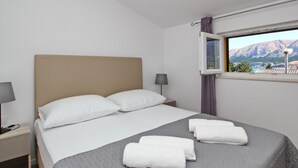 Ein Hotelzimmer mit Bett, Nachttisch, Lampe und Fenster mit Bergblick.