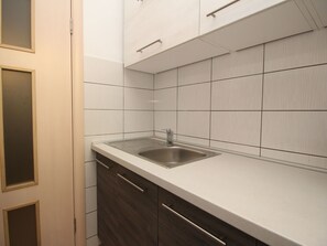 A modern kitchen with a stainless steel sink, white tiles, and wooden cabinets. - Charmante Wohnung in Baška mit Eigener Terrasse by Interhome (Krk/Baška)