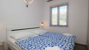 Ein ordentlich gemachtes Bett mit einer blauen und weißen Bettdecke, einem weißen Kopfkissen und einem gefalteten weißen Handtuch.
