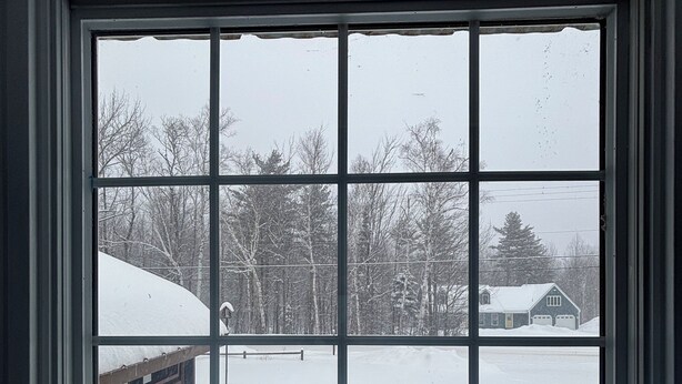 A window with a view of a snowy landscape, including trees and a house. - Walk to the slopes from this BMOM 3 bedroom. (Rumford)