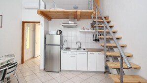 Una cocina compacta con estufa integrada, un refrigerador y una escalera de madera.