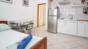 Una cocina compacta con refrigerador, pileta y techo de madera.
