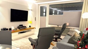 Ein modernes Wohnzimmer mit Fernseher, Couchtisch, Sofa und einem Weihnachtsbaum.