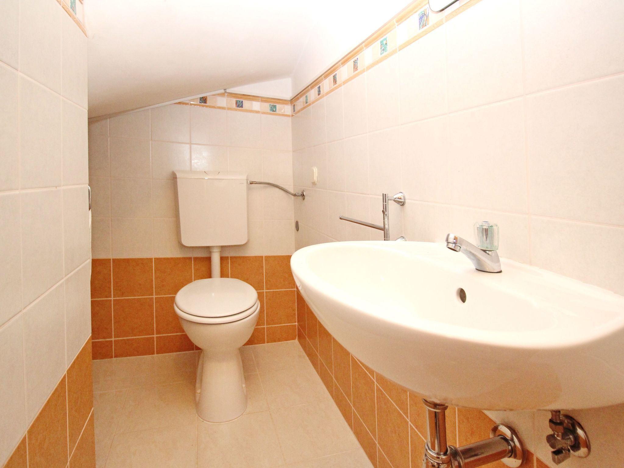 Een badkamer met toilet, wastafel en betegelde wanden.