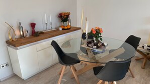 Une cuisine moderne avec une table ronde en verre, des chaises noires et un plan de travail en bois.