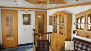 Een kamer met een houten trap, een grote kast, een bank en een kamerbreed tapijt.