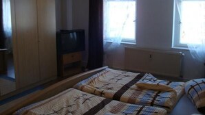 Une chambre à coucher avec un lit, une télévision et une armoire.