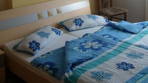 Une chambre avec un plafond en pente, un lit avec une literie à motifs floraux, une chaise et un luminaire fixé au mur.